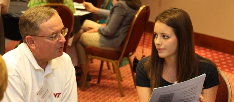 Image of an alumni and student at a table in conversation