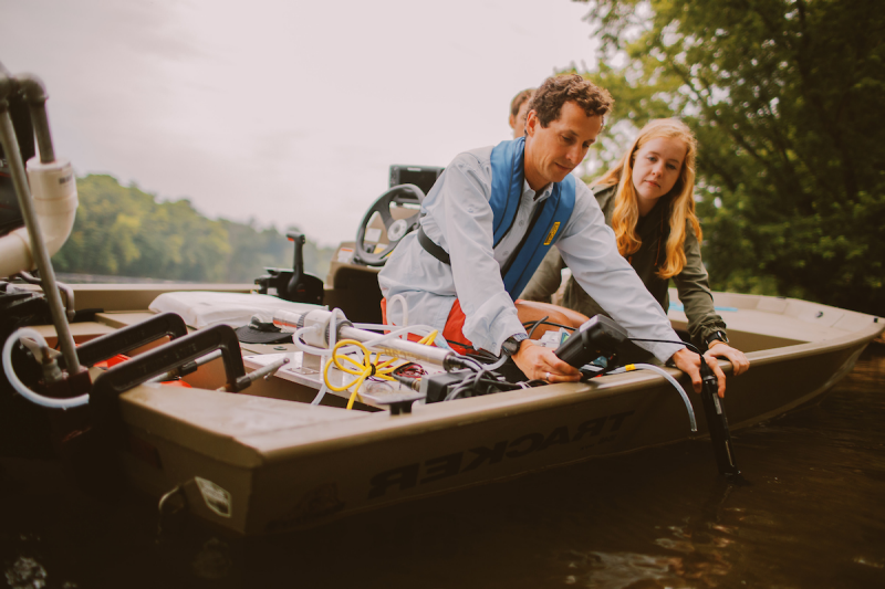 Image of Durrelle Scott and his graduate student taking water samples on the New River as part of his research that uses data to examine how climate change has impacted flooding in the U.S.