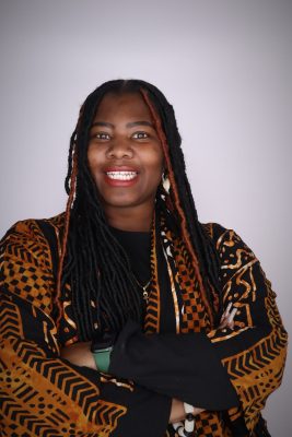 Woman of color with long braids with arms crossed and smiling