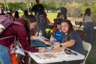 Photo of a student signing a paper at a student booth