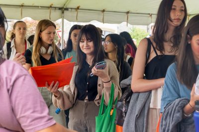 Students in line at a table stand, with on student grabbing an orange bag
