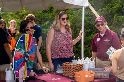 A photo of a professor with two colleagues standing at their booth 