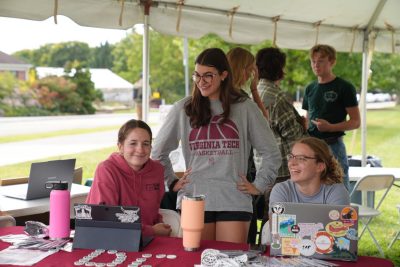 A group photos of 3 female students smiling at their table stand