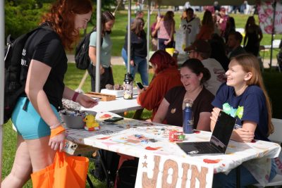 Photo of a student talking to two other students at a table stand