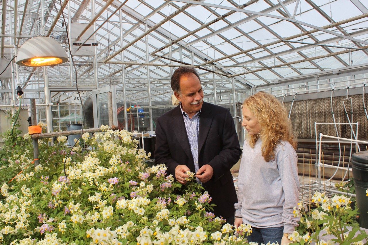 A professor and a student in a greenhouse.