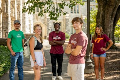 Five college students standing and smiling at the camera.